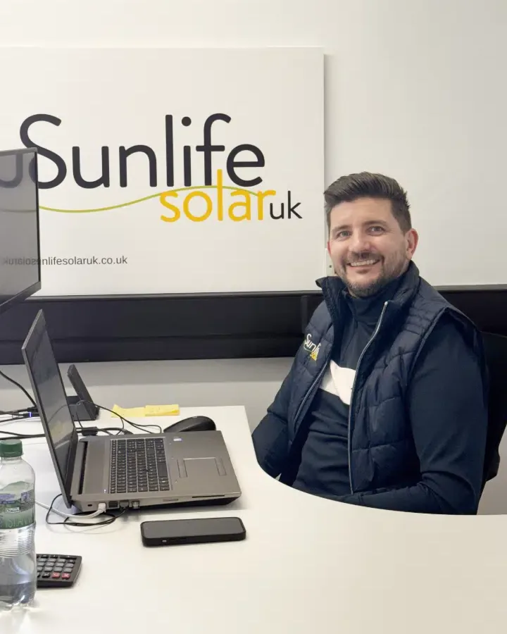 A member of the Sunlife Solar UK team at a desk in the East Malling office, with the company sign on the wall behind.